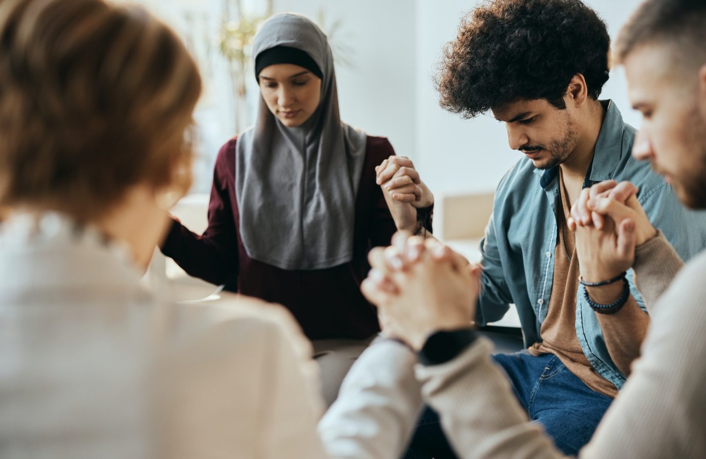 multi-ethnic-attenders-of-group-therapy-holding-hands-during-counseling-at-mental-health-center-.jpg